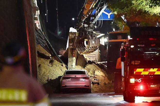 수도권 등 중부지역에 호우주의보가 발효된 지난 16일 오후 경기 오산시 가장교차로 고가도로 옹벽이 무너져 소방관들이 매몰된 차량을 구조작업하고 있다.ⓒ뉴시스