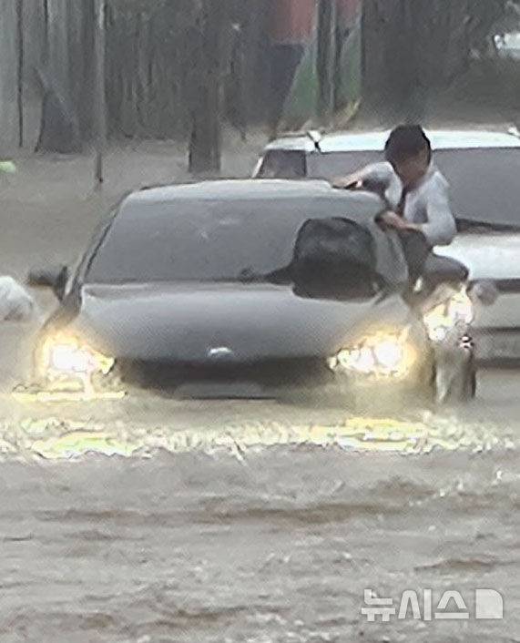 [광주=뉴시스] 이영주 기자 = 광주지역에 시간당 86㎜ 폭우가 쏟아진 17일 오후 광주 북구청 앞 교차로에서 차량들이 폭우로 넘치는 빗물에 갇혀 오가지 못하고 있다. 한 운전자가 차량에서 탈출을 시도하고 있다. 2025.07.17. leeyj2578@newsis.com