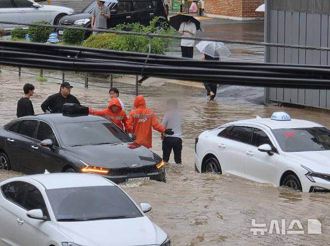 [광주=뉴시스] 광주지역에 시간당 86㎜ 폭우가 쏟아진 17일 오후 광주 북구청 주변에서 소방당국이 불어난 빗물에 고립된 차량 운전자를 구조하고 있다. (사진 = 광주 북구 제공) 2025.07.17. photo@newsis.com