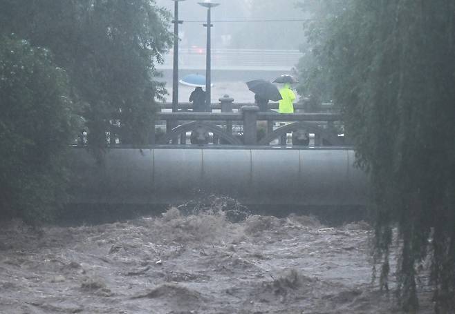호우경보가 내려진 17일 오후 광주 동구 호남동 부동교 일대 광주천 강물이 범람 수위까지 도달, 시민들이 불어난 강물을 바라보고 있다. 뉴시스
