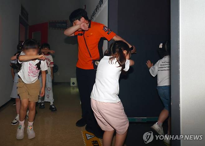 화재 대피는 이렇게 (부산=연합뉴스) 손형주 기자 = 16일 부산 동래구 온천동 부산119안전체험관에서 초등학교 1학년 학생들이 화재 발생시 좁은 복도를 탈출하는 교육을 받고 있다. 최근 부산에서 부모가 외출한 사이 발생한 아파트 화재로 자매가 잇따라 숨지는 일이 발생했다. 이 사건을 계기로 교육부와 교육청, 소방청 등 관계기관은 아동을 대상으로 화재 대응 및 안전 교육을 강화하겠다고 발표했다. 2025.7.16 handbrother@yna.co.kr