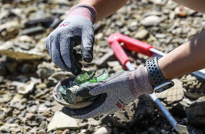 깨진 병 조각들을 조개 껍질에 담아 치우고 있다. 김성룡 기자