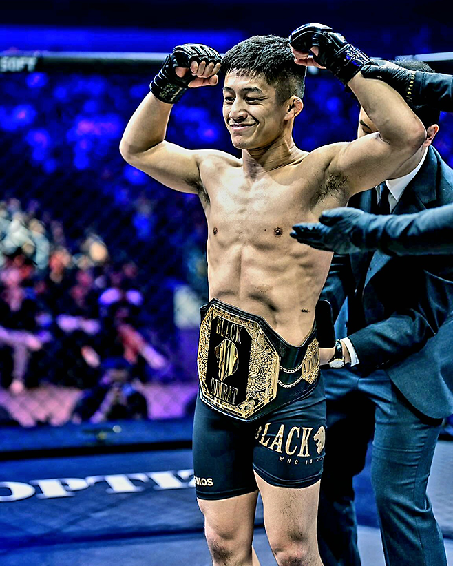 제3대 블랙컴뱃 플라이급 챔피언 ‘탱크’ 고마키네 다카히로가 2025년 5월 인천광역시 영종국제도시 인스파이어 아레나에서 타이틀 1차 방어 성공 후 기뻐하고 있다. 오른쪽은 챔피언 벨트를 채워주는 블랙컴뱃 박평화 대표. 사진=이데아 파라곤