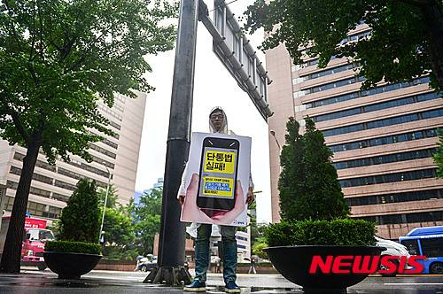 【서울=뉴시스】김선웅 인턴기자 = 13일 오전 서울 중구 SK텔레콤 본사에서 참여연대 심현덕 간사가 통신요금 인하를 요구하는 1인 시위를 하고 있다. 참여연대는 이 날 1인 시위에서 단말기 가격인하, 요금인가제 폐지 중단, 기본요금제 폐지, 통신비 인하를 요구했다. 2015.07.13. lassoft2@newsis.com