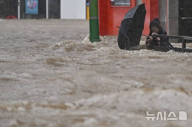 [광주=뉴시스] 이영주 기자 = 사진은 폭우가 쏟아진 지난 17일 오후 침수된 광주 북구청 앞 도로에서 한 시민이 물살에 휩쓸리고 있는 모습. 2025.07.17. leeyj2578@newsis.com
