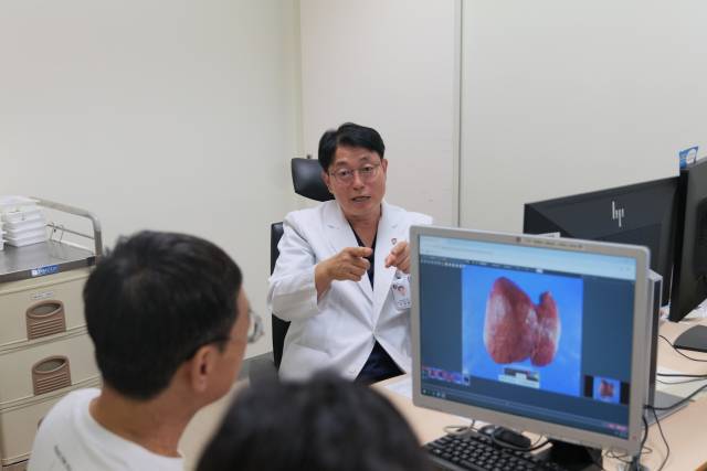 이광웅 서울대병원 간담췌외과 교수가 간이식 수혜자 오 모씨에게 로봇 간이식 과정에 대해 설명하고 있다. 사진 제공=서울대병원