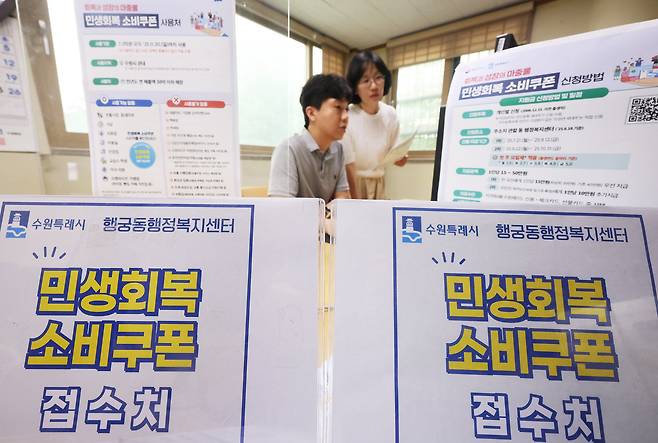 17일 경기도 수원시 팔달구 행궁동 행정복지센터에서 공무원들이 오는 21일 시작되는 민생회복 소비쿠폰 신청을 앞두고 안내문 등을 점검하고 있다.     신용·체크카드 지급을 원하는 국민은 자신이 이용 중인 카드사의 누리집이나 앱, 콜센터와 ARS 등을 통해 온라인으로 신청하거나, 카드와 연계된 은행영업점을 방문해서 신청하면 된다. /연합뉴스