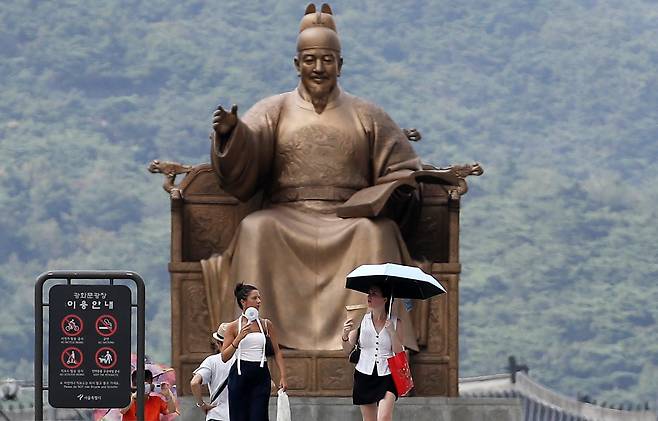 서울 종로구 광화문광장에서 외국인 관광객들이 휴대용 선풍기로 더위를 식히며 걷고 있다. /뉴스1