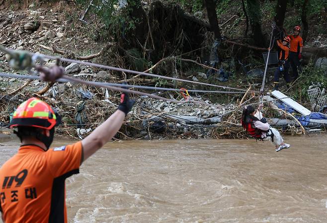 반려견 꼭 안고 탈출 경기 가평군 마일리의 캠핑장을 방문했던 시민들이 20일 집중호우로 도로가 끊기는 바람에 고립됐다가 119구조대에 의해 구조되고 있다. 연합뉴스