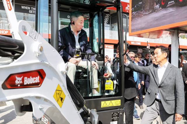 박정원(왼쪽) 두산그룹 회장이 올해 4월 독일 뮌헨에서 열린 건설기계 전시회 ’바우마 2025’에서 두산밥캣 미니굴착기 신제품에 탑승했다. [두산밥캣 제공]