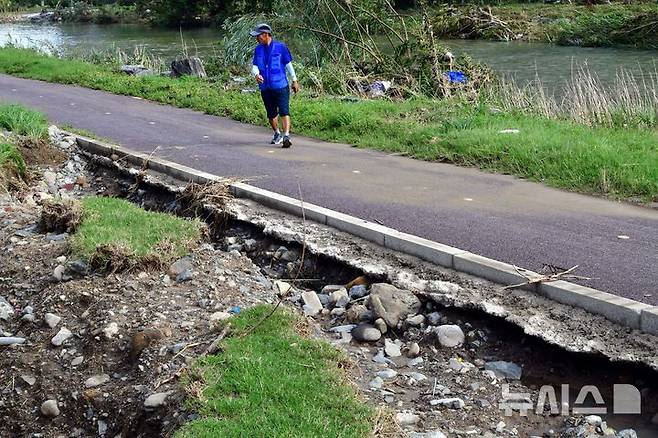 [광주=뉴시스] 이현행 기자 = 20일 오전 광주 서구 광주천 인근 산책로에서 한 시민이 하천 범람으로 인해 지반이 붕괴된 현장을 지나고 있다. 2025.07.20. lhh@newsis.com