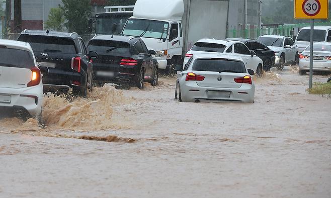지난 17일 천안시 광덕면의 한 국도에서 소방대원들이 침수된 차량을 살펴보고 있다. 뉴시스