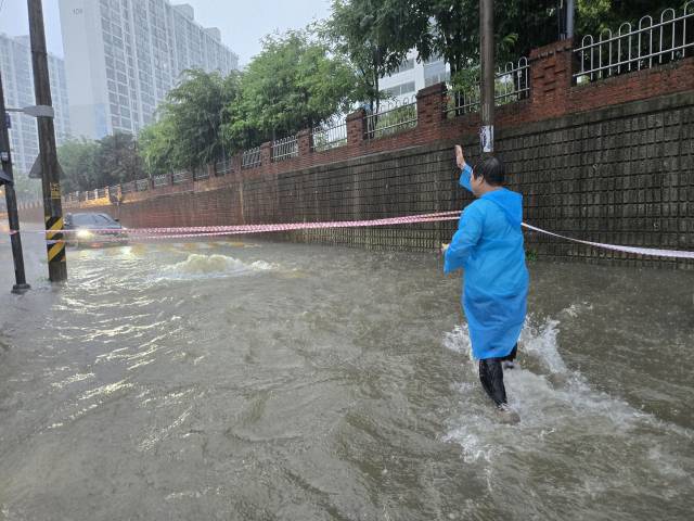 지난 17일 광주 금호동 어린이보호구역이 역대급 폭우로 인해 침수된 가운데 안형주 광주 서구의원이 현장으로 뛰어 들어 차량 통제를 하고 있다. 사진 제공=독자