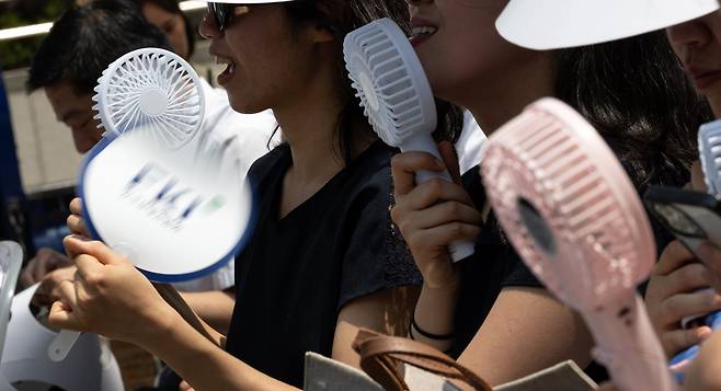 지난 8일 오전 서울 중구 청계광장에서 열린 'K-바캉스 캠페인' 개회식 참석자들이 미니 선풍기와 부채로 더위를 식히고 있다. /뉴스1