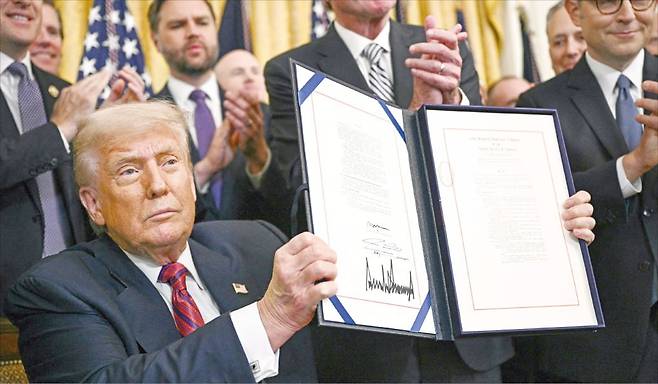 < ‘지니어스법’ 서명한 트럼프 > 도널드 트럼프 미국 대통령이 지난 18일 백악관에서 ﻿‘지니어스법’에 서명한 뒤 이를 들어 보이고 있다.  AFP연합뉴스