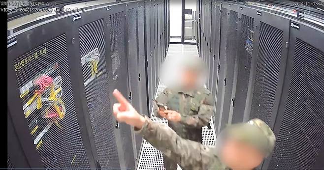 국회 행정안전위원회가 공개한 12·3 불법계엄 당일 중앙선거관리위원회 폐쇄회로(CC) TV 영상에서 계엄군들이 선관위 시스템 서버를 가리키고 촬영하고 있다. 국회 행정안전위원회 제공