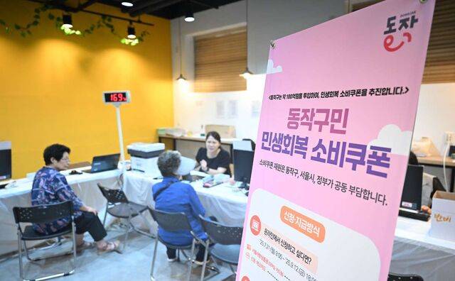 민생회복 소비쿠폰 신청 첫날인 21일 서울 동작구 대방동주민센터 작은도서관에서 시민들이 신청 안내를 받고 있다. 이날 온라인 신청이 가능한 인터넷 홈페이지 접속이 지연되고, 일부 행정복지센터에서 전산 오류가 나는 등 신청에 차질이 생긴 곳이 많았다. 이한형 기자