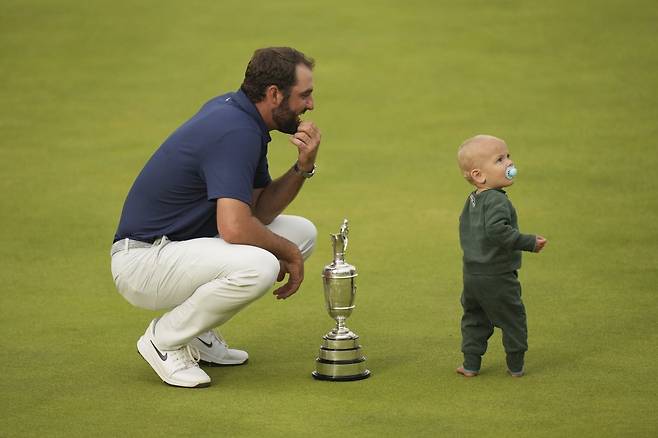스코티 셰플러가 생애 처음으로&nbsp;디 오픈 정상에 선 뒤 우승자에게 주는&nbsp;클라레 저그를 앞에 두고 18번 홀 그린에서 아들과 함께 즐거운 시간을 보내고 있다.  포트러시(영 북아일랜드) | AP뉴시스