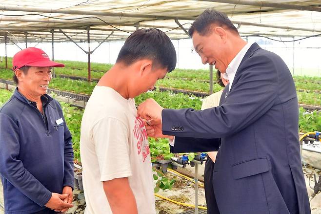 외국인 계절근로자에 한글 명찰 달아주는 김한종 장성군수. 전남 장성군 제공.