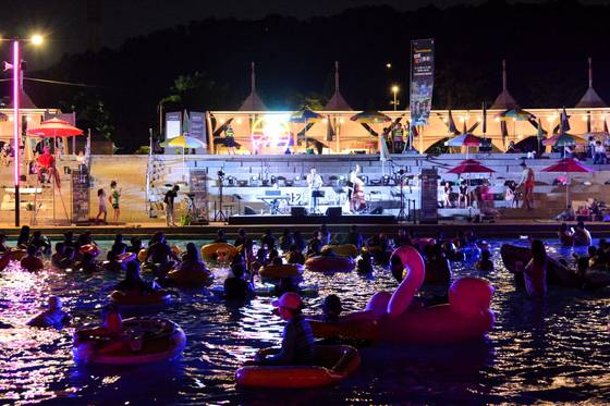 Participants at last year's ″2024 Hangang Festival_Summer,″ enjoy “Hangang Cinema Pongdang,” a floating movie theater where people lounge on tubes to watch films on a giant screen. [SEOUL METROPOLITAN GOVERNMENT]