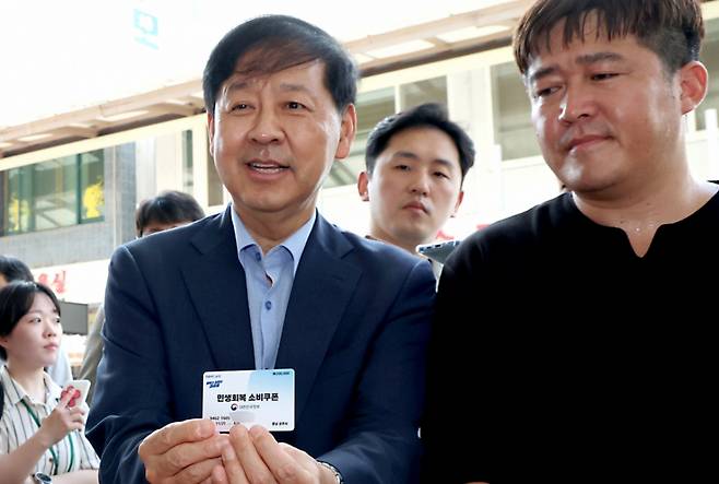 구윤철 경제부총리 겸 기획재정부 장관이 21일 오후 민생회복 소비쿠폰 시행 첫날 충남 공주시 산성시장을 방문 과일가게등 재래시장 소비쿠폰 사용을 점검하며 소비쿠폰으로 과일을 구매하러 나온 시민과 카드를 들어 보이고 있다./사진제공=뉴스1