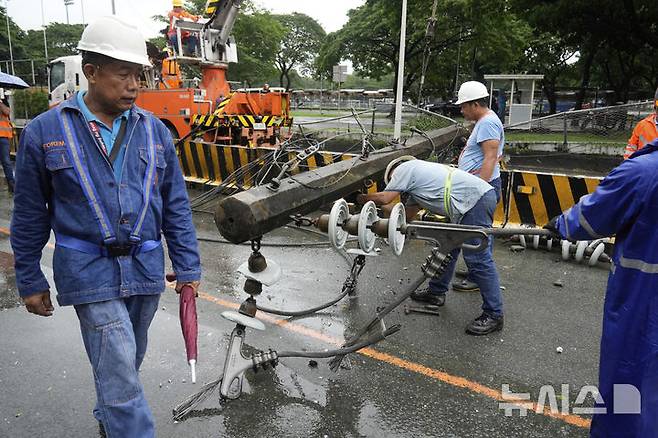 [케손=AP/뉴시스] 19일(현지 시간) 필리핀 케손시에서 관계자들이 제6호 태풍 위파 영향으로 무너진 전신주를 복구하고 있다. 2025.07.22.
