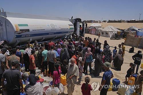 지난 19일(현지시간) 가자지구 남부 칸유니스 구호소 물탱크 트럭 앞에 물을 받으려고 모인 팔레스타인 주민들.[AP=연합뉴스. 재판매 및 DB 금지]