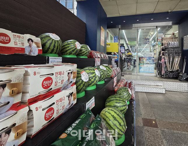 신림역 인근 한 편의점 입구에 수박, 햇반, 계란 등 생필품과 제철 과일이 전면 진열돼 있다. 민생쿠폰 지급 이후 식재료 수요가 늘며 고가 품목까지 매대 구성에 포함되고 있다. (사진=한전진 기자)