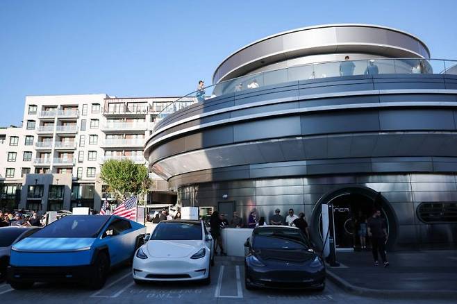 21일(현지시간) 미국 캘리포니아주 로스앤젤레스(LA)에 처음 문을 연 테슬라의 식당 겸 휴게소 '다이너(Diner)'에 입장하려는 시민들이 대기하는 동안 테슬라 전기차가 충전되고 있다. AFP연합뉴스