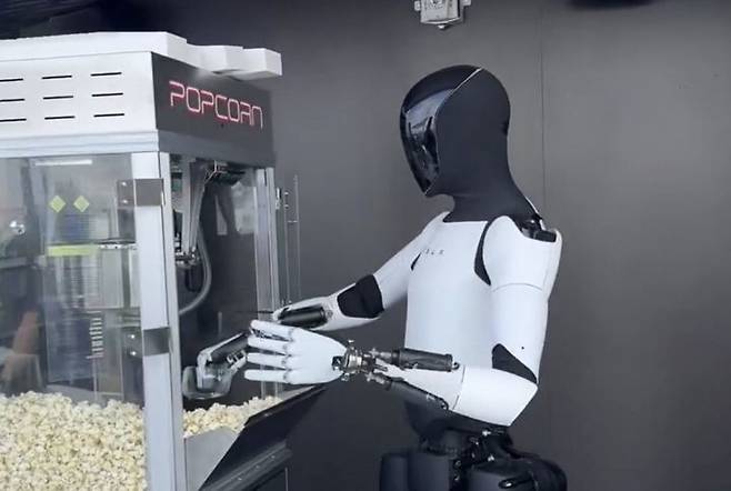 미국 전기차기업 테슬라가 개발 중인 휴머노이드 로봇 ‘옵티머스’가 22일(현지 시간) 캘리포니아주 로스앤젤레스에서 팝콘을 담는 모습. 테슬라는 이날 식당과 전기차 충전소를 접목한 휴게소 형태의 복합시설 ‘다이너’를 열었다. 사진 출처: ‘X’ 캡처