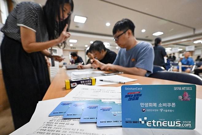 이재명 정부 첫 대규모 경기부양책인 민생회복 소비쿠폰(민생쿠폰) 신청 첫 날인 21일 서울 양천구 신정3동주민센터에서 시민들이 접수를 하고 있다. 민생쿠폰은 오는 9월 12일까지 온·오프라인을 통해 1차 신청을 받는다. 지원금액은 국민 1인당 기본 15만원이며 차상위 계층과 한부모가족은 1인당 30만원, 기초생활수급자는 1인당 40만원을 받는다.  이동근기자 foto@etnews.com