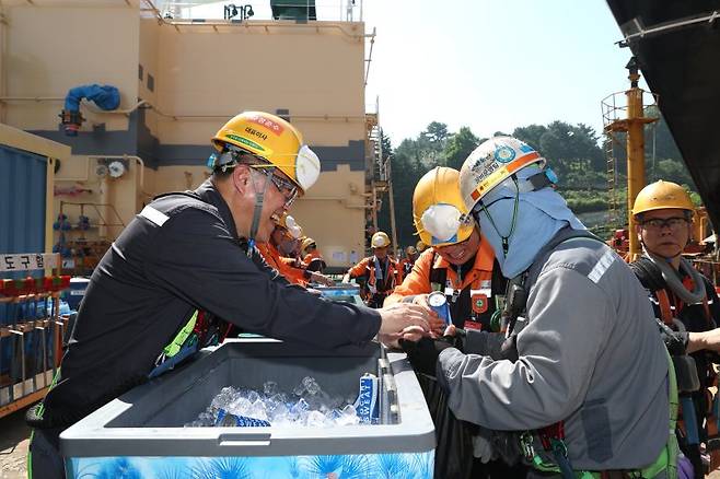 한화오션 김희철 대표이사(왼쪽)가 23일 한화오션 경남 거제사업장 1도크 인근에서 근로자들에게 시원한 음료를 건네주고 있다. 한화오션 제공