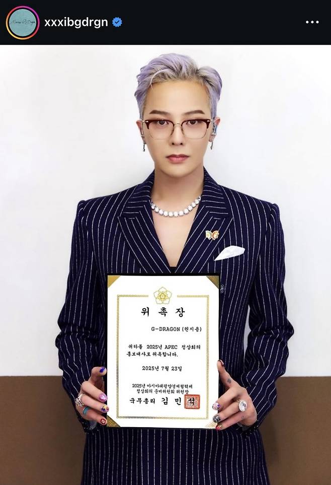 김민석 국무총리는 23일 가수 지드래곤을 올해 10월 말 경북 경주에서 열리는 아시아태평양경제협력체(APEC) 정상회의 홍보대사로 위촉한다고 밝혔다. 사진은 이날 자신의 사회관계망서비스(SNS)에 APEC 홍보대사 위촉장을 든 모습을 공개한 지드래곤. 지드래곤 SNS 캡처.