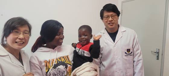 '2025 JW성천상' 수상자인 강동원(맨 오른쪽)·전진경 부부 의사가 22일 짐바브웨 현지 진료실에서 소아 뇌성마비 환자와 환하게 웃고 있다. 사진 강동원·전진경 제공
