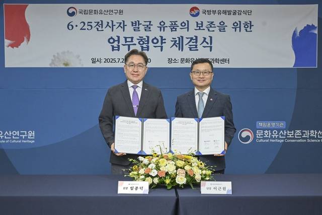 이근원(오른쪽)국방부유해발굴감식단장과 임종덕(왼쪽) 국립문화유산연구원장이 22일 6·25전사자 발굴 유품의 보존을 위한 업무협약서’에 서명하고 기념사진을 촬영하고 있다. 국방부 제공