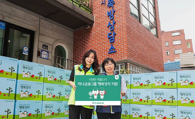 하나금융그룹 직원이 김나나(오른쪽) 서울특별시립 창신동쪽방상담소장에게 행복상자를 전달하며 기념촬영을 하고 있다. [하나금융그룹 제공]