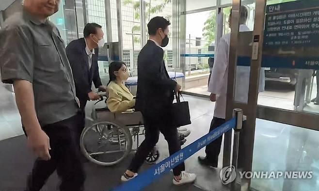 김건희 여사가 지난 6월 27일 서울 송파구 서울아산병원에서 윤석열 전 대통령이 미는 휠체어에 탄 채 퇴원하고 있다. 연합뉴스