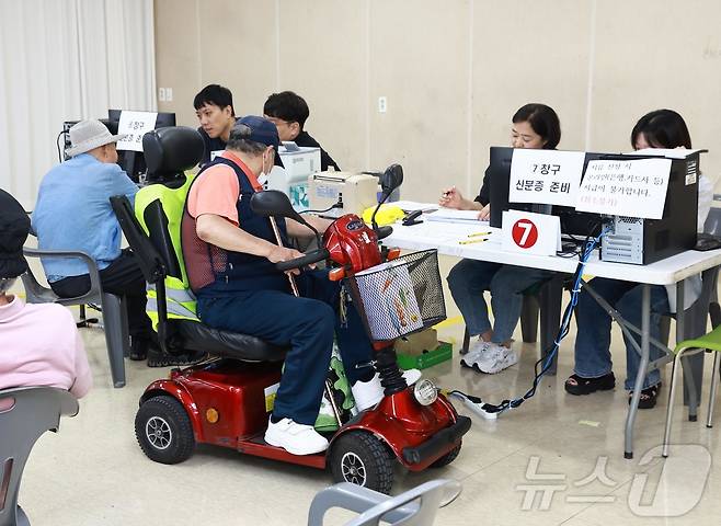 전 국민을 대상으로 지원하는 민생회복 소비쿠폰 신청 사흘째인 23일 오전 전남 화순군 군민종합문화센터에 마련된 화순읍 접수창구에서 한 어르신이 전동스쿠터를 타고 쿠폰을 신청하고 있다.(화순군 제공, 재배포 및 DB 금지) /뉴스1