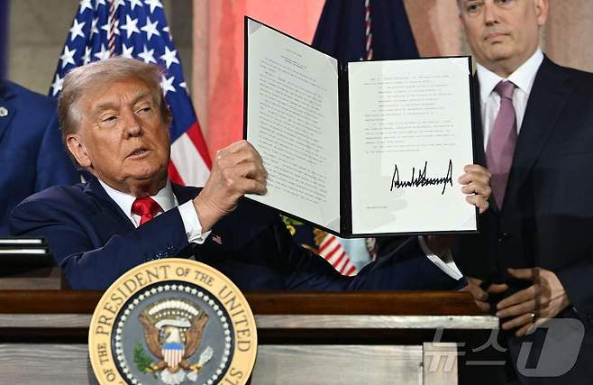 23일(현지시간) 미국 워싱턴 D.C.의 앤드루 W. 멜론 오디토리움에서 열린 ‘AI 경쟁에서 승리하기(Winning the AI Race)’ 정상회의에서 도널드 트럼프 미국 대통령이 AI 관련 행정명령에 서명한 후 이를 공개했다. 이 행정명령은 미국이 글로벌 AI 경쟁에서 우위를 확보하기 위한 전략의 일환으로, 규제 완화와 기술 수출 확대 등을 포함하고 있다. ⓒ AFP=뉴스1