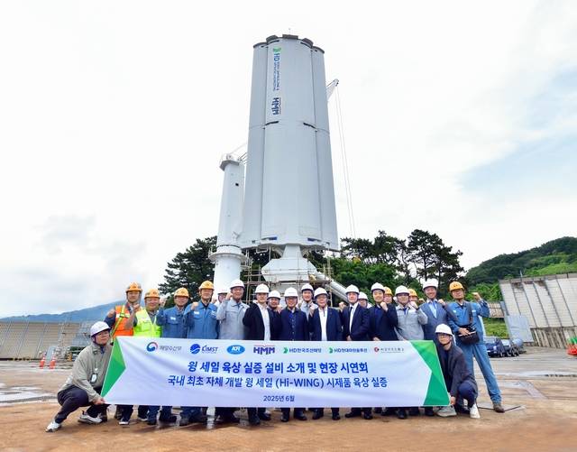 HD한국조선해양이 지난달 16일 경남 창원에서 자체 개발한 윙세일(제품명 Hi-WING) 시제품의 육상 실증 시연회를 진행, 참석자들이 기념촬영을 하고 있다. HD현대 제공.