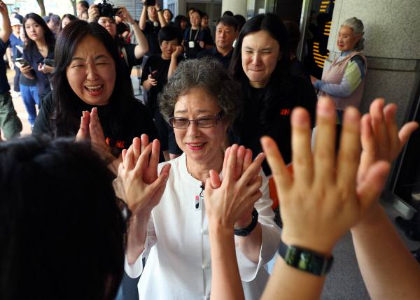 최 씨가 23일 부산지법에서 열린 재심 첫 공판을 마치고 법정을 나서며 변호인과 여성단체 회원들의 축하를 받고 있다. 연합뉴스
