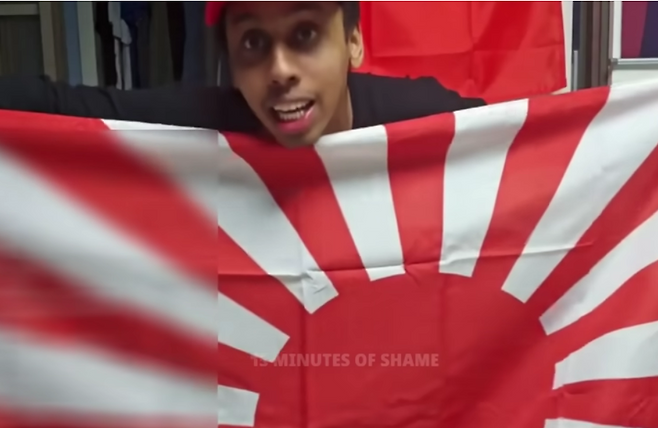 미국인 유튜버 조니 소말리가 일본 제국주의의 상징인 전범기 ‘욱일기’를 꺼내 들며  “일본은 다시 한국을 점령해야 한다”라고 도발하는 모습. [유튜브 채널 ‘15 minutes of shame’ 갈무리]
