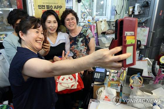 김혜경 여사가 25일 인천 계양산전통시장을 방문해 과일을 구매한 뒤 상인들과 기념촬영을 하고 있다. 〈사진=대통령실통신사진기자단·연합뉴스〉