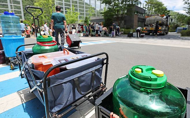 지난 21일 수돗물이 끊긴 울산시 울주군 언양읍 한 아파트 주민들이 살수차에서 물을 받기 위해 각종 통을 들고 줄을 서 있다. 연합뉴스