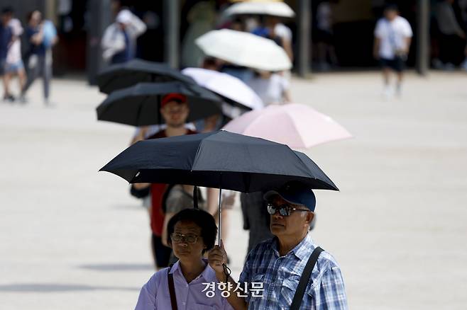 서울의 한낮 기온이 34도로 폭염이 이어지고 있는 지난 24일 서울 종로구 경복궁에서 관광객들이 양산을 쓴 채 햇살을 피하고 있다. 문재원 기자