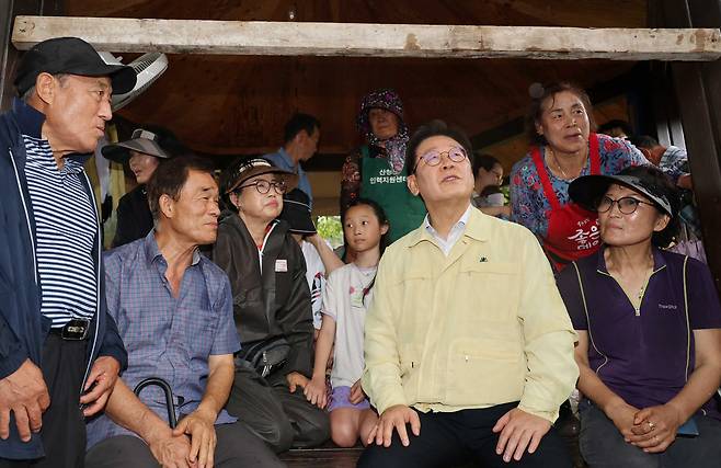 President Lee Jae Myung, second from right, talks to residents of Sancheong County, South Gyeongsang, on July 21, after heavy rainfall led to a landslide and flooding in the area. [JOINT PRESS CORPS]