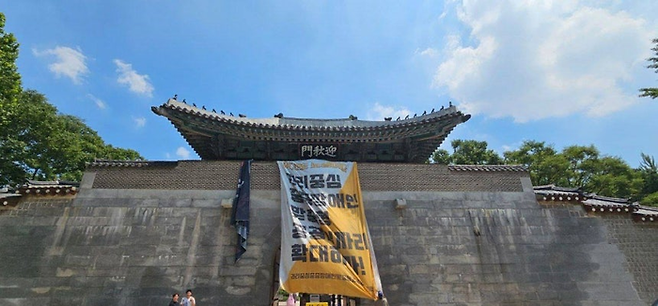 25일 오후 12시 20분께 서울 종로구 경복궁 영추문에 전장연이 내건 대형 현수막이 걸려있다. [사진 = 전장연 제공]