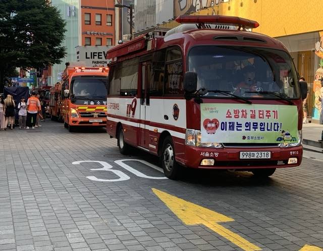 지난 24일 서울 중구 명동관광특구에서 진행된 ‘소방출동로 확보 훈련’ 도중 소방차가 길목을 지나가고 있다. 중구청 제공