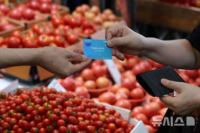 [서울=뉴시스] 조성우 기자 = 지난 23일 서울 시내의 한 전통시장에서 한 시민이 민생회복 소비쿠폰을 이용해 과일을 구매하고 있다. 2025.07.23. xconfind@newsis.com