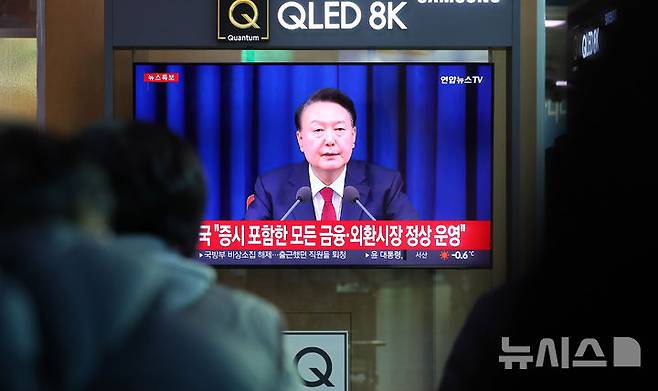 [서울=뉴시스] 김혜진 기자 = 윤석열 대통령이 비상계엄 해제를 선언한 지난해 12월4일 오전 서울역 대합실에서 시민들이 관련 뉴스를 보고 있다. 2024.12.04. jini@newsis.com